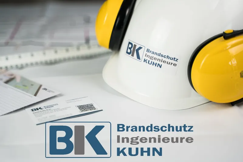 Schutzhelm mit Gehörschutz und Logo der Brandschutzingenieure Kuhn, daneben Visitenkarten und das BIK-Logo